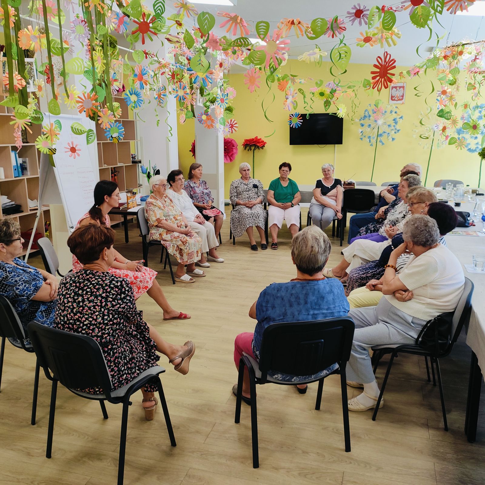 Seniorzy siedzący na krzesłach w kółku